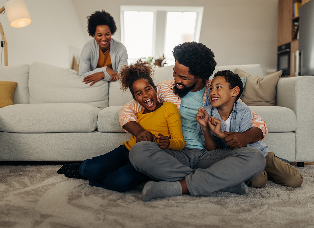 Insurance Solutions - Portrait of a Cheerful African American Family with a Young Son and Daughter Having Fun Spending Time Together in the Living Room