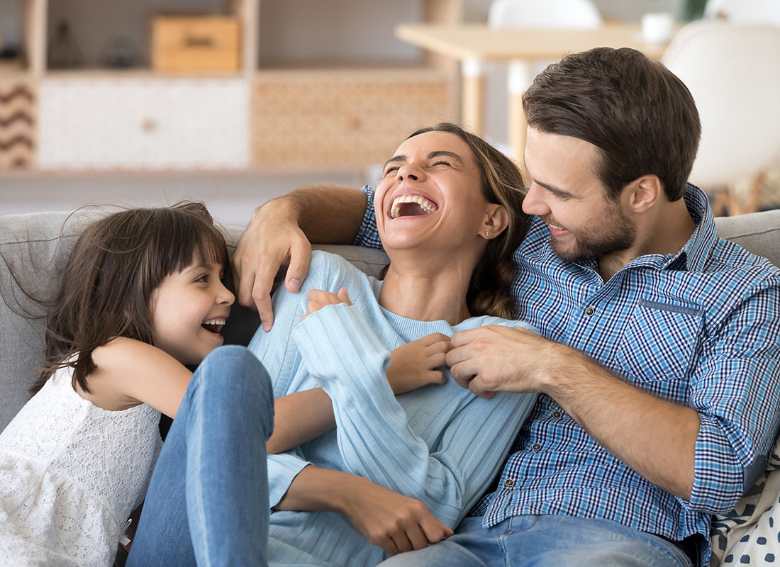 We Are Independent - Laughing Mom Spending Time Together with Her Husband and Daughter Sitting on the Sofa at Home
